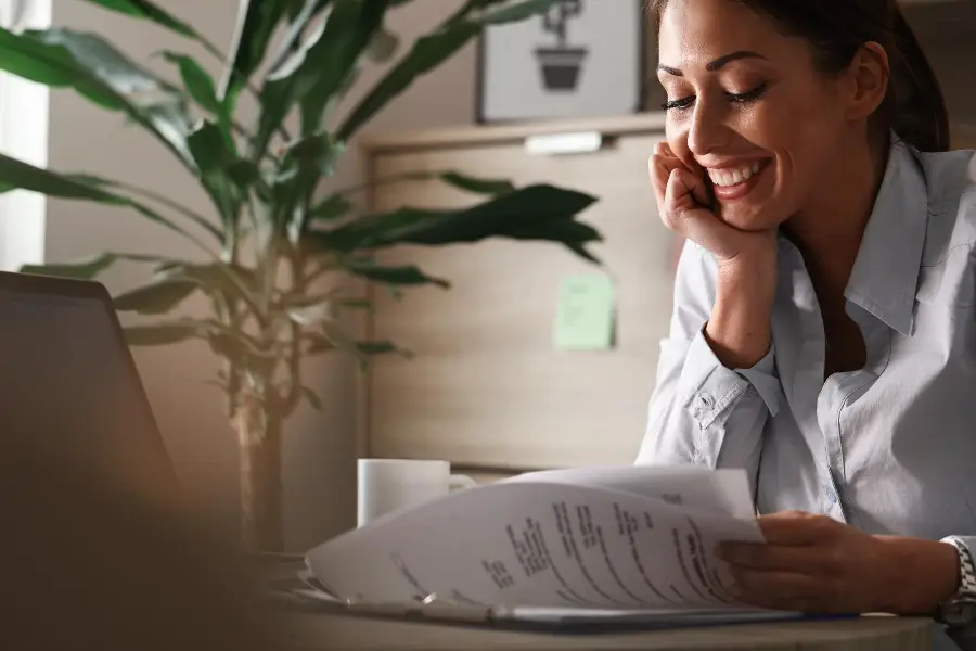 Happy female entrepreneur analyzing business reports and feeling satisfied about the business progress